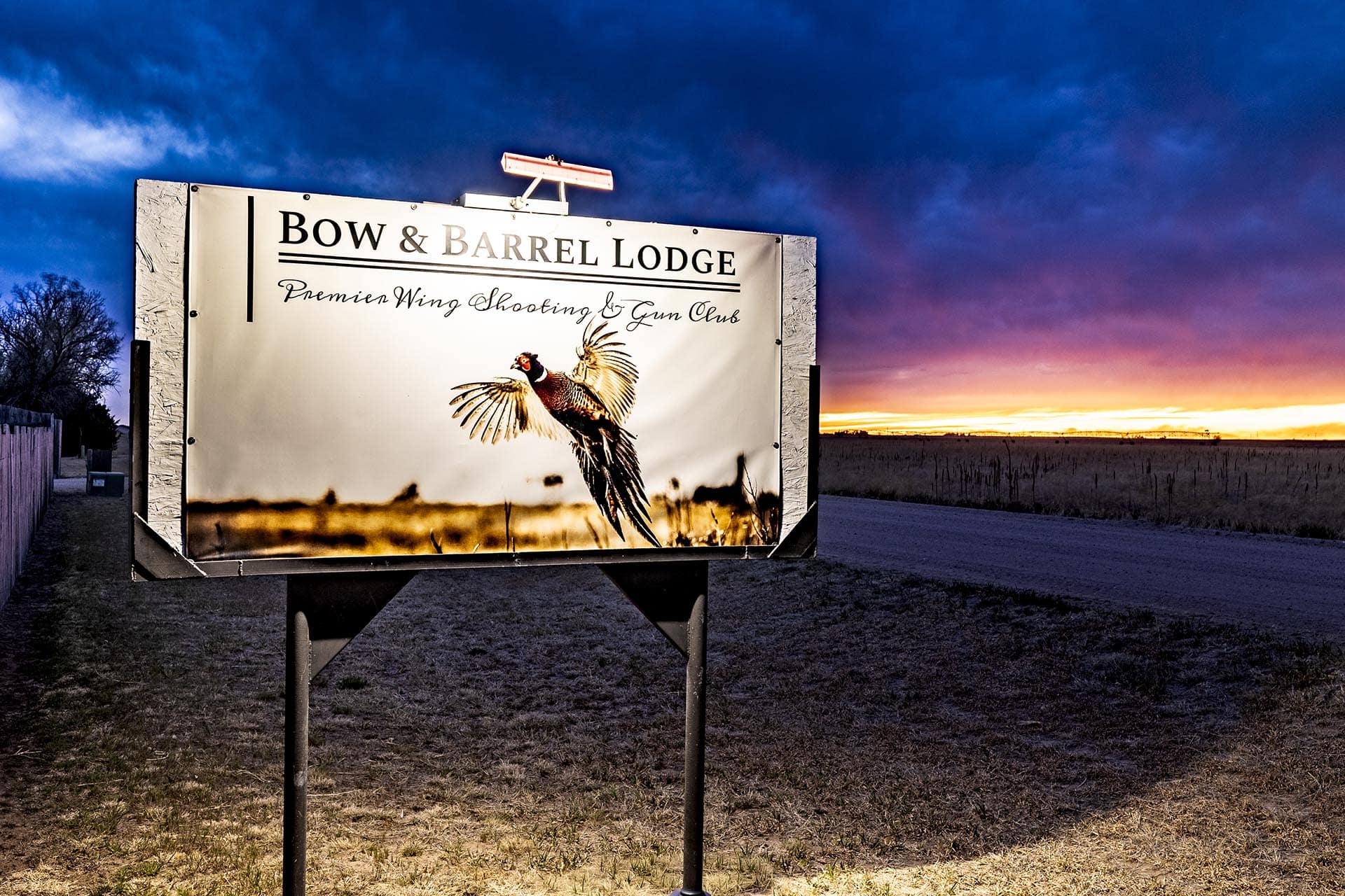 Signboard for Bow & Barrel Lodge advertising Premier Wing Shooting & Gun Club with a pheasant image at sunset.