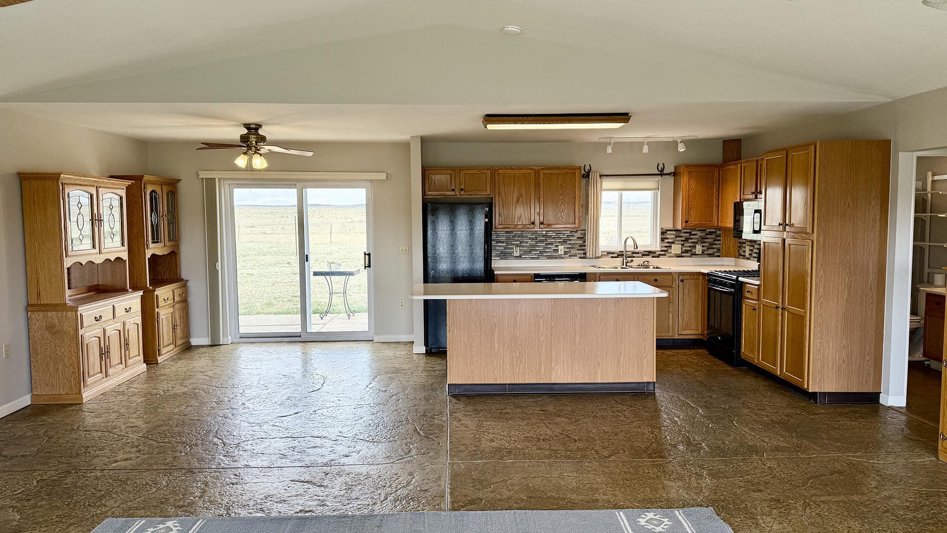 Open-concept kitchen with a central island, oak cabinets, and a sliding glass door to the yard.