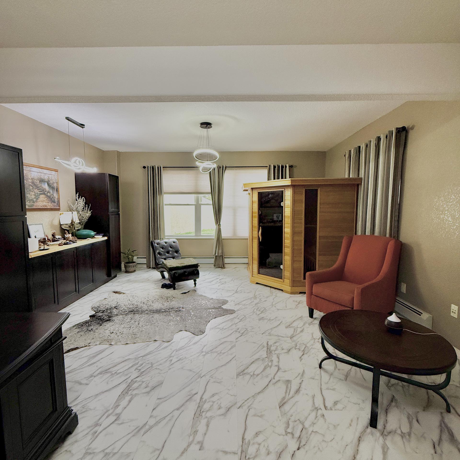 Living room with marble floor, dark storage along left wall, a wooden display cabinet, and red upholstered chairs under a round pendant light? fixture(s).