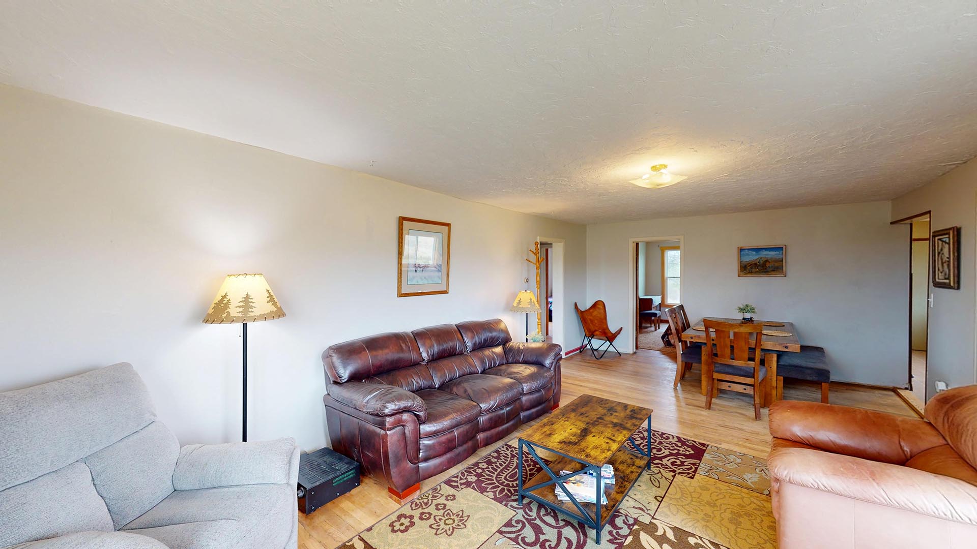 Cozy living room with a brown leather sofa, a grey recliner, a wooden coffee table, and a patterned area rug.