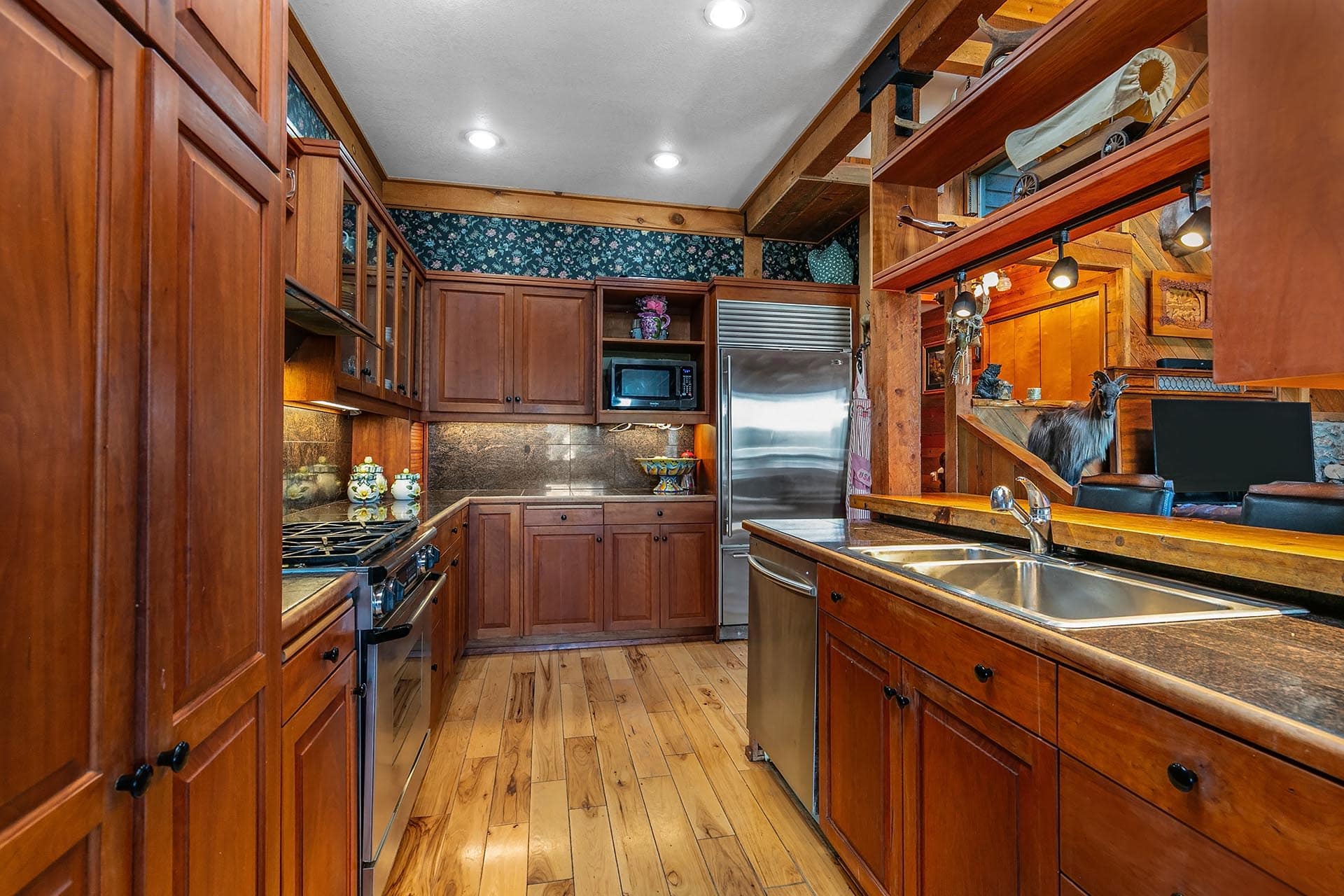Rustic kitchen with warm wood cabinets, island, and stainless steel appliances.