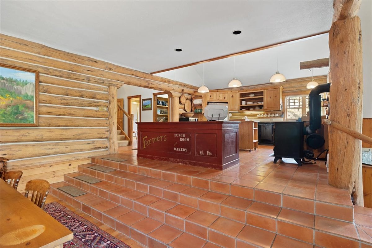 Rustic log cabin cafe with terracotta steps, a red bakery counter reading 'Farmers Lunch Room Bakery'.