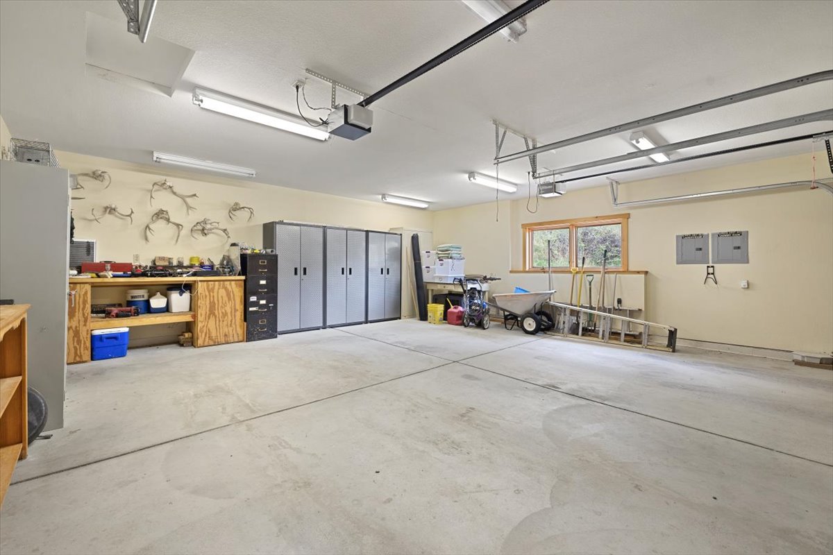Spacious garage/workshop with tool benches, grey storage cabinets, and various supplies neatly organized along the wall.