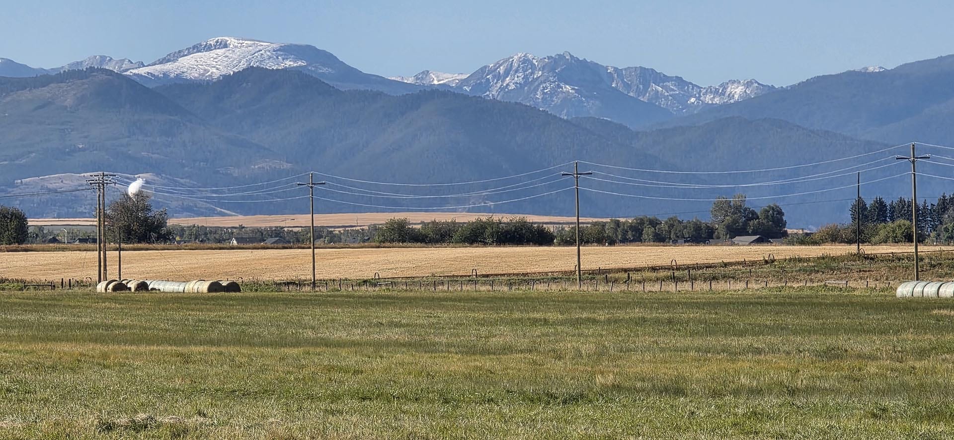 harvested crop field with power lines montana west bozeman homestead