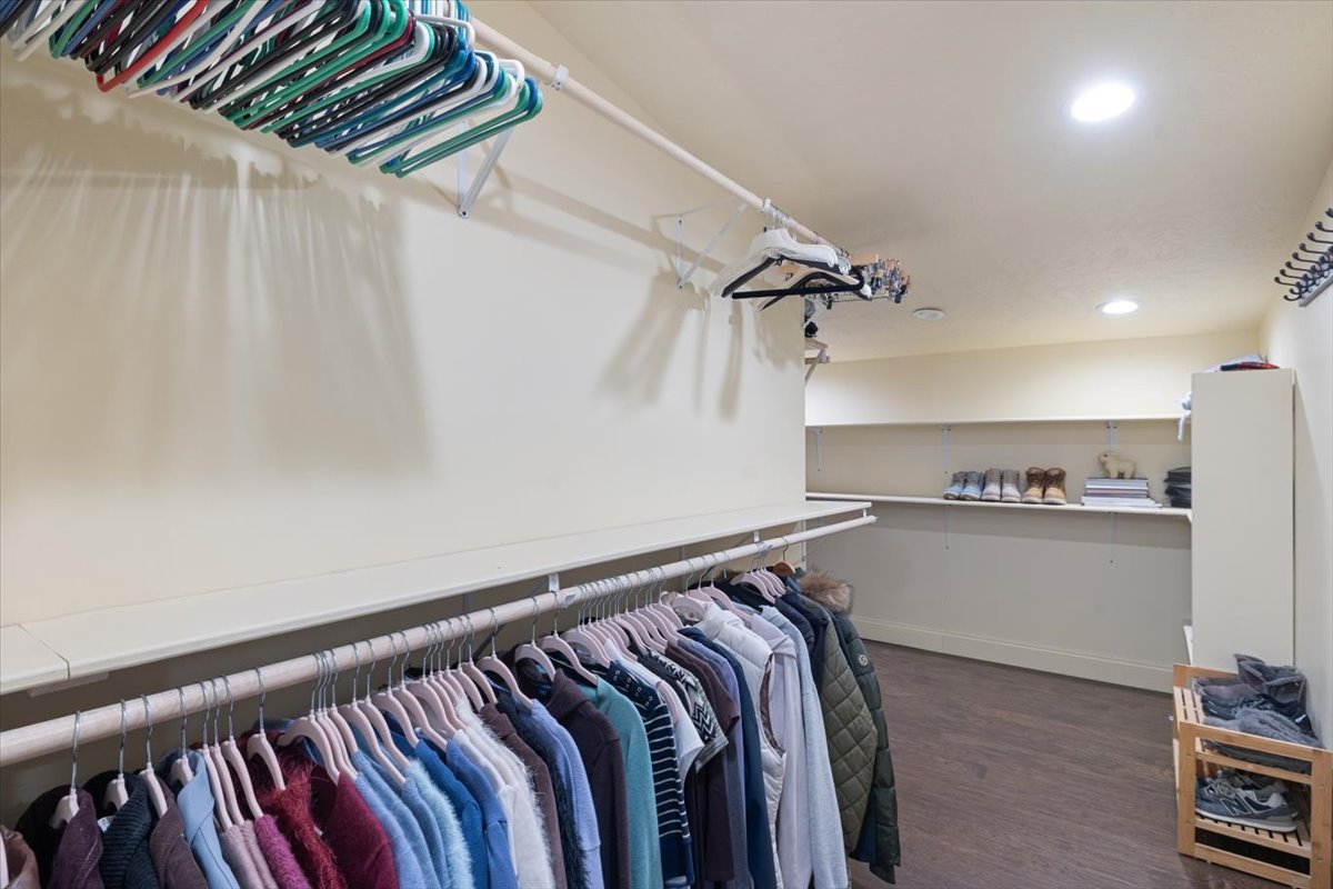 Interior of a walk-in closet with hanging clothes and shelves.