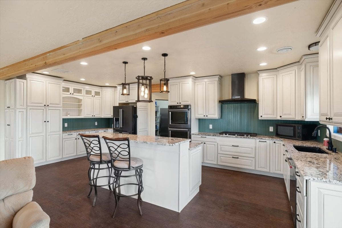 Spacious modern kitchen with white cabinetry, island, and stainless steel appliances.