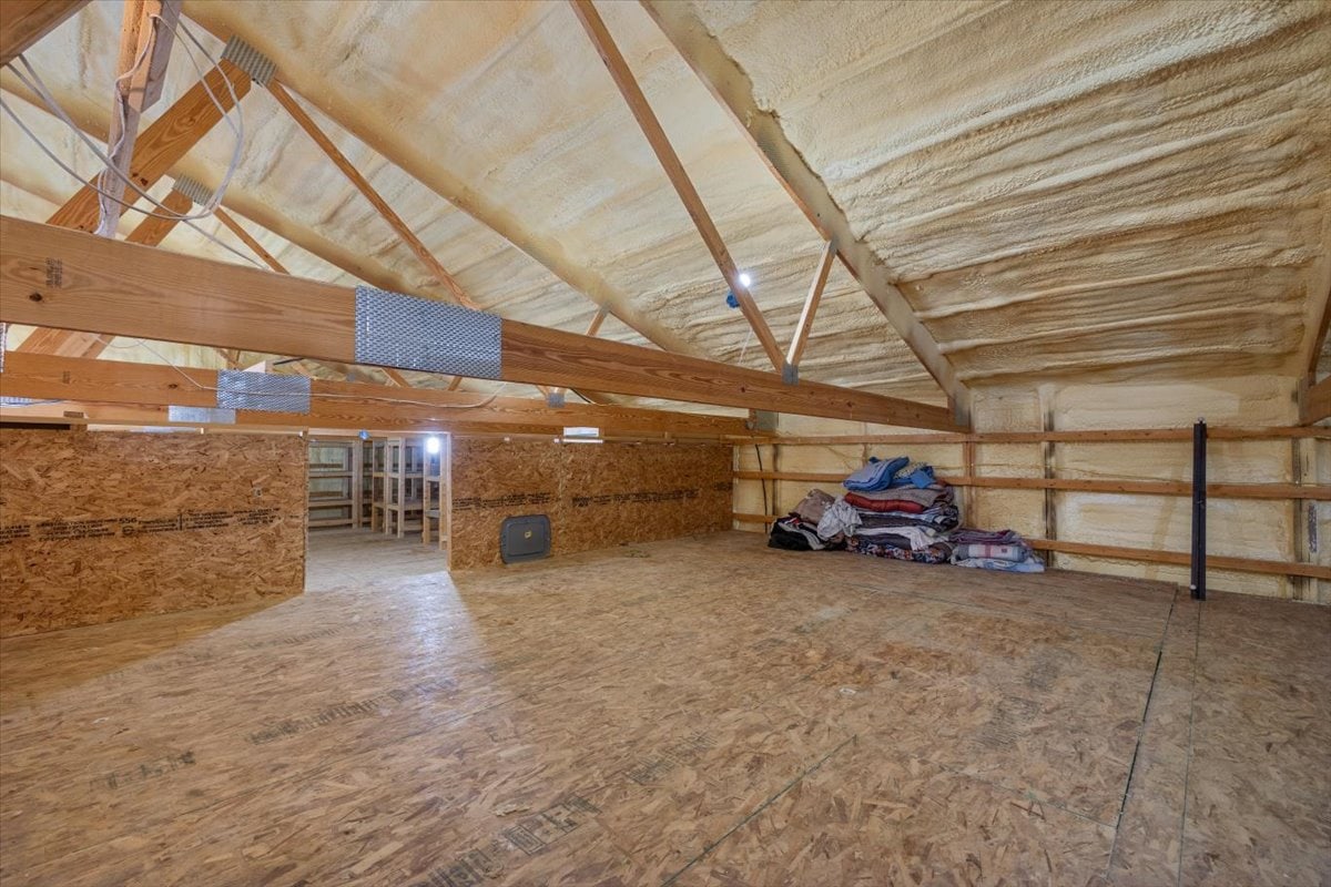 Spacious interior with wooden beams and insulation, unfinished construction site.